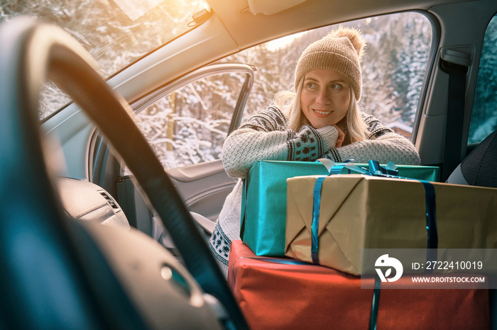 Woman Giving Gifts. Female is holding presents and delivering them on her car to Home. Holidays concept. Driving car in Christmas Eve. People In A Snow-Covered Forest. Sunny Cold Winter Day.