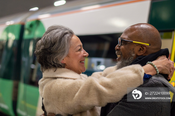 Senior couple embracing at train station