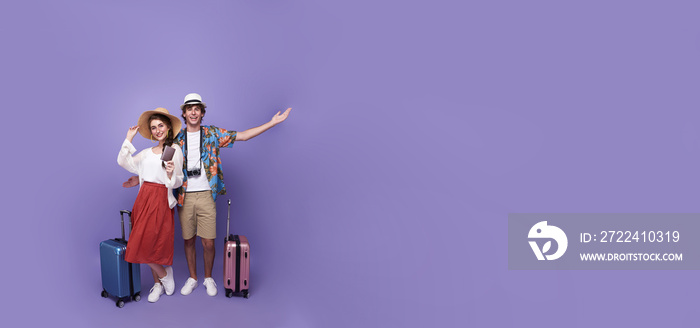 Happy excited couple tourist with baggage going to travel on holidays isolated on copy space purple background.