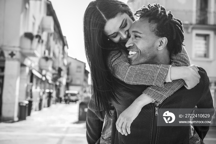 African couple having fun outdoor in city tour - Young influencers people lovers enjoying time together - Love, fashion, travel and relationship concept - Focus on man face - Black and white editing