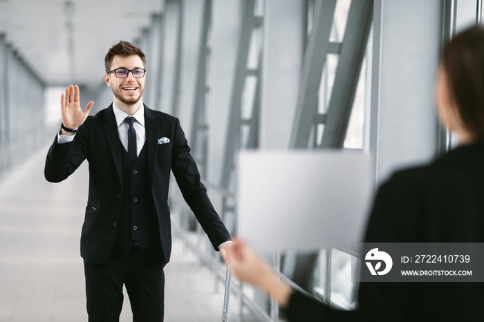 Man waving to partner who waiting for him with signboard