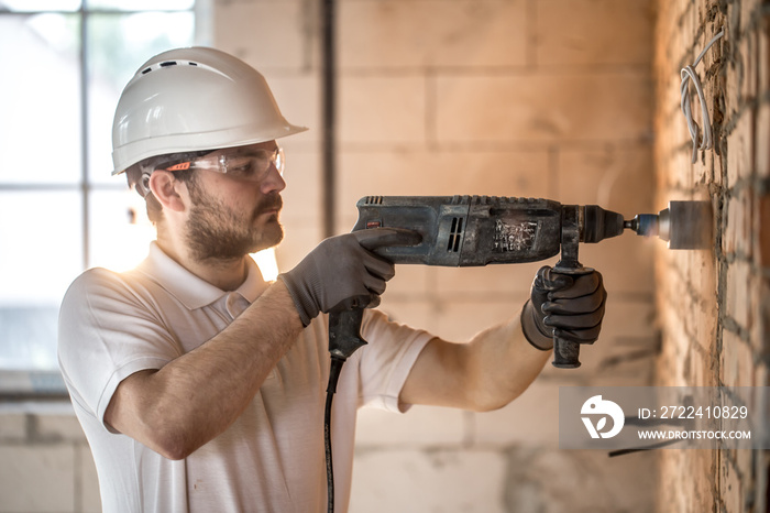 Handyman uses jackhammer, for installation, professional worker on the construction site. The concept of electrician and handyman.