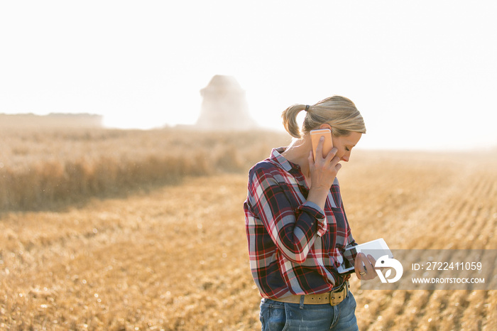 Modern female farmer with tablet on her wheat field