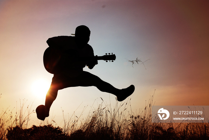 Abstract beautiful man playing Guitar in the foreground on sky background.