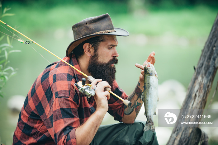 Portrait of young bearded man fishing at a lake or river. Flyfishing. Fishing hobby and spring weekend.