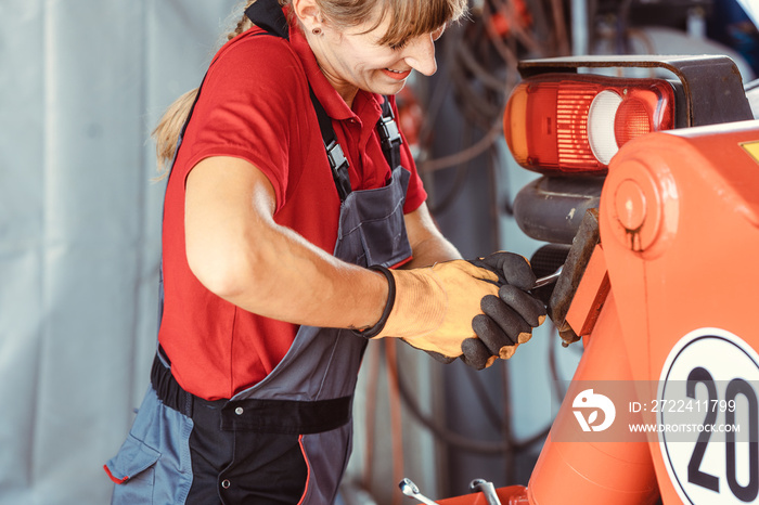 Woman machinist working with wrench of a farm machine