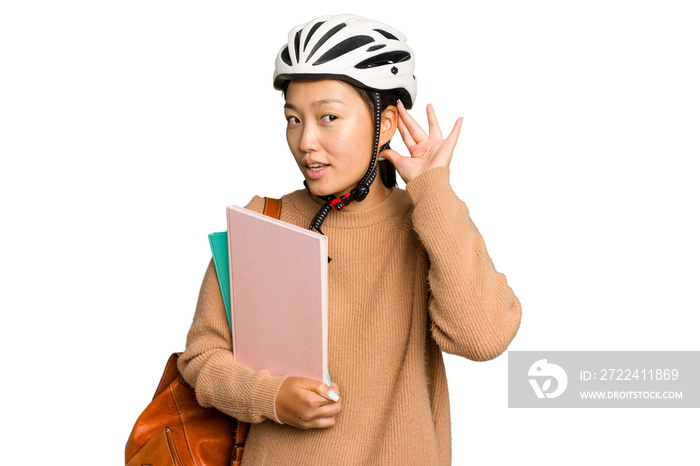 Young student asian woman wearing a bike helmet isolated on green chroma background trying to listening a gossip.