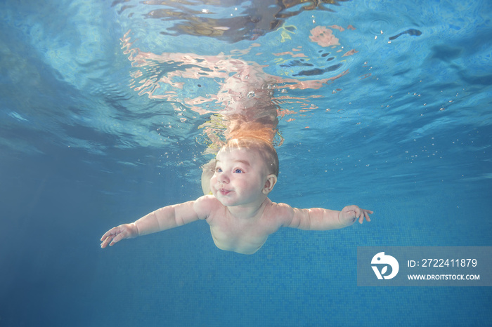 Little baby boy learning to swim underwater in a swimming pool. Healthy family lifestyle and children water sports activity. Child development, disease prevention
