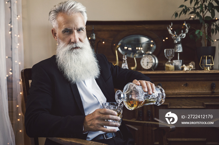 Handsome bearded senior man pouring whiskey into the glass