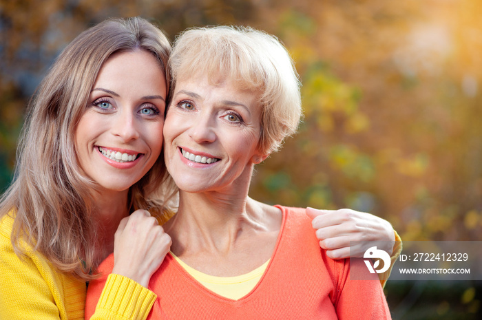 Outdoor portrait of smiling happy senior mother with her adult daughter