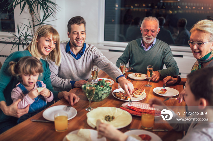 Multi generation family enjoying meal around table at home