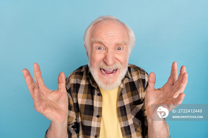 Photo of angry irritated man pensioner dressed checkered shirt screaming rising arms isolated blue color background