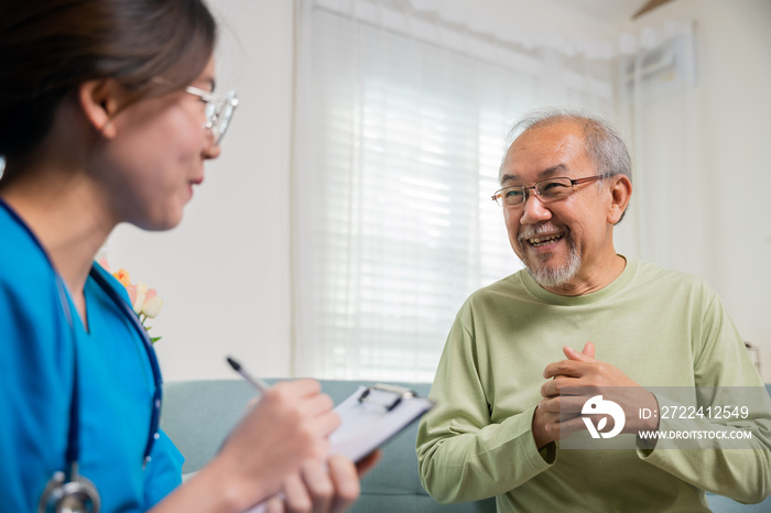 Asian young nurse writing prescription during home visit sick elder old man, Senior man takes doctor at home telling about health complaints, health care and medical concept