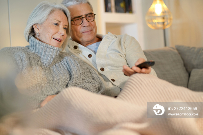 Attractive senior couple on couch at home watching TV