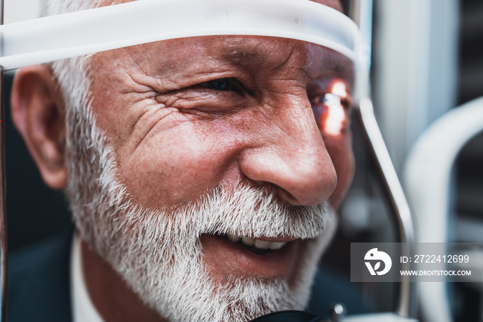 Elegant senior bearded man receiving ophthalmology treatment. Doctor ophthalmologist checking his eyesight with modern equipment.