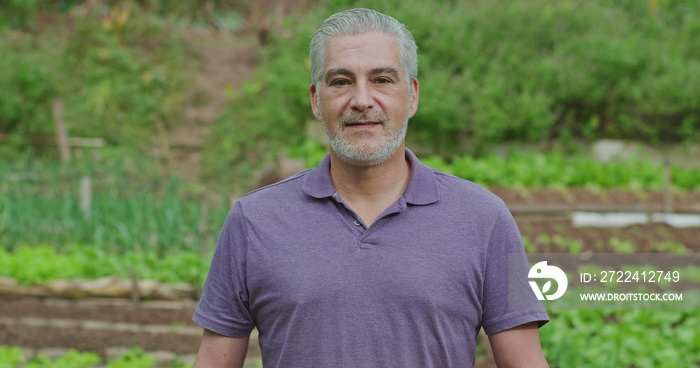 Portrait of a middle aged man standing outside in green field looking at camera. An older male person in late 50s