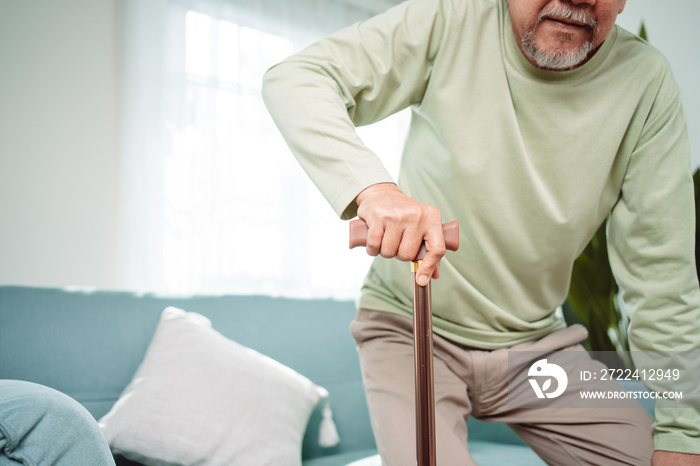 Asian Senior elderly old man disabled patient walking slowly his use walker or cane in living room at home. Feeling painful and suffering from knee pain. Healthcare medical and insurance concept.