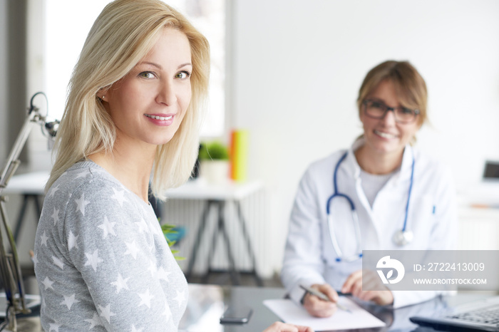 Doctor and her patient. Shot of a middle aged smiling female doctor sitting in front of laptop and meeting with her patient.