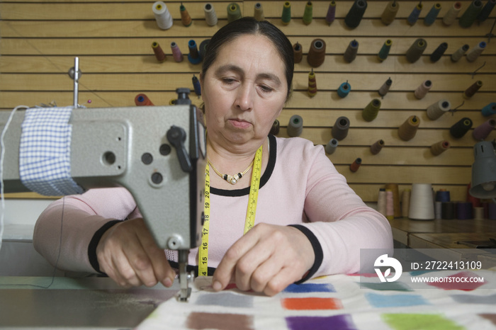 Middle aged woman using a sewing machine in laundry