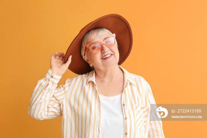 Portrait of stylish senior woman on color background