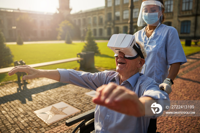 Smiling senior man using virtual reality device outdoors