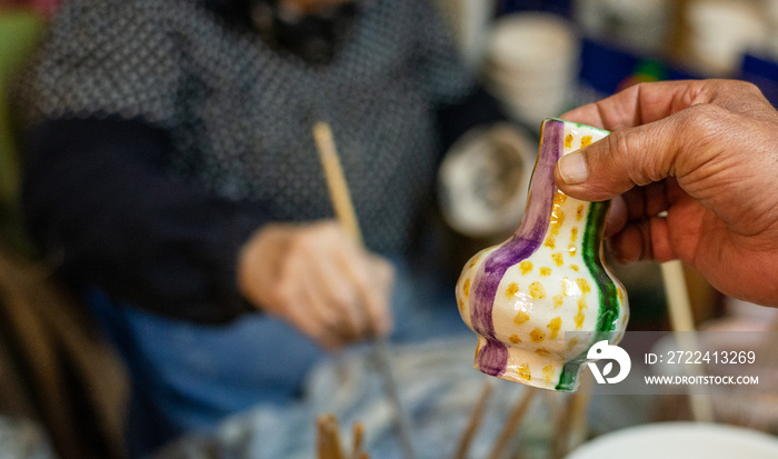 elderly craftswoman painting earthenware in her pottery workshop