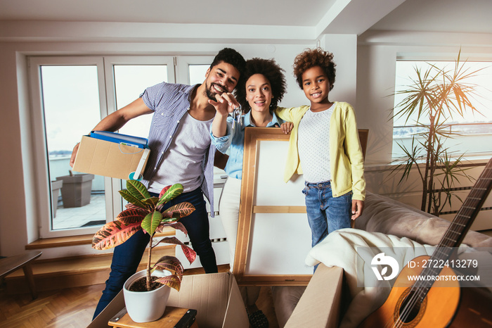 African American family, parents and daughter, unpacking boxes and moving into a new home, having fun.