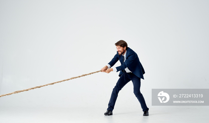 business man in a suit pulls the rope studio light background