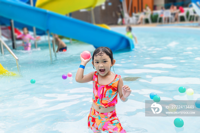 Portrait image of 4-5 years old baby. Happy Asian child girl swimming and play water in the blue pool. She smile and laugh. Summer season.