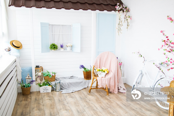 Interior with vintage house with veranda, furniture, bright spring studio with beautiful decor, flowers in wicker baskets. White interior of studio of cottage for photo shoot in style of Provence.