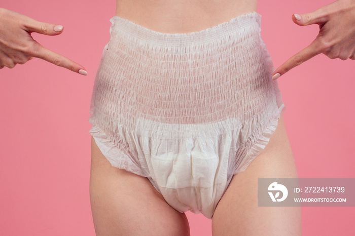 young redhaired ginger woman wearing incontinence diaper in studio pink background