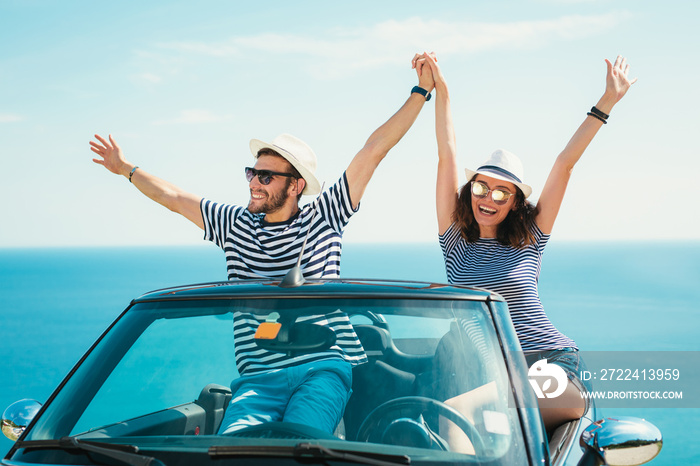 Young attractive couple posing in a convertible car, by the sea