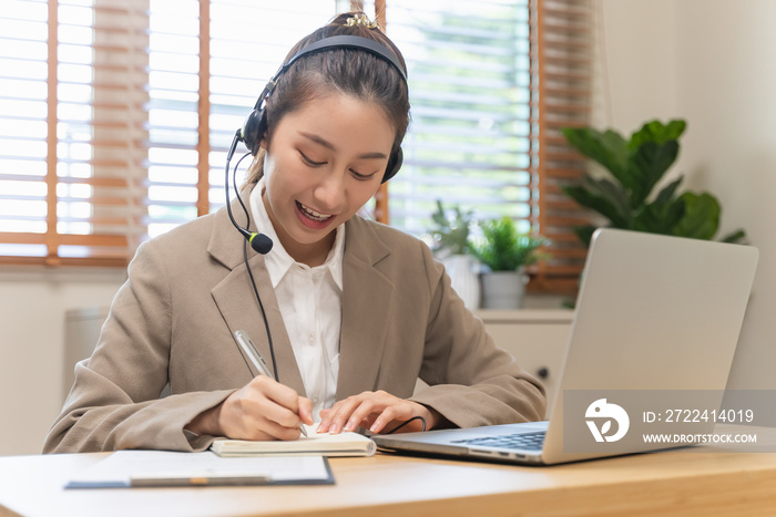 Happy young asian business woman waving hands to greeting partner during making video conference with her team.