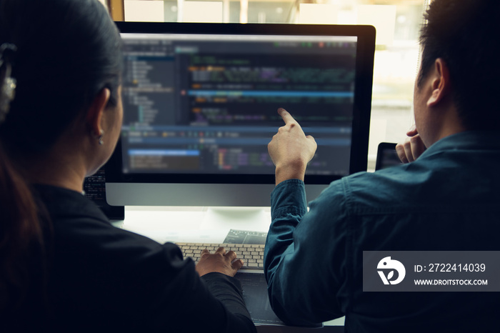Two software developers are analyzing together about the code written into the program on the computer.
