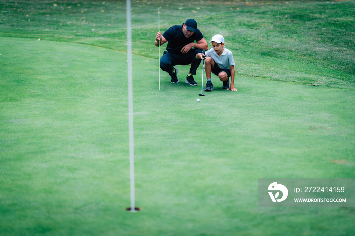 Golf Putting Training. Golf Instructor with Young Boy Practicing on the Putting Green