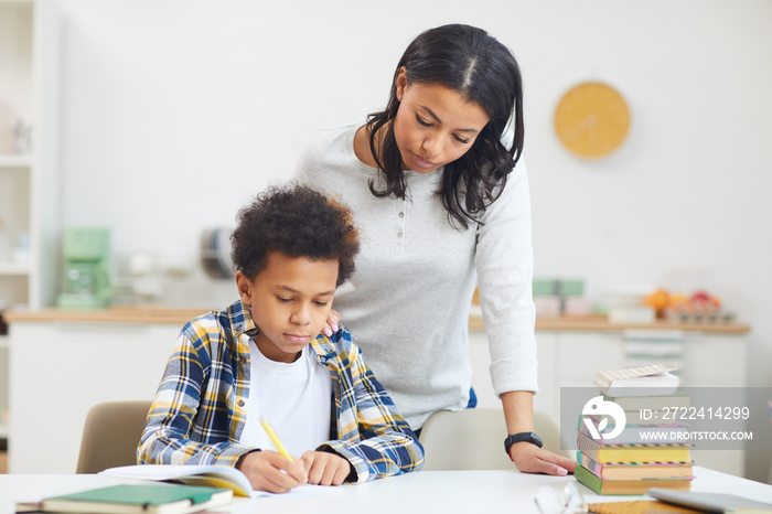 Portrait of young African-American mother helping boy while studying at home, copy space