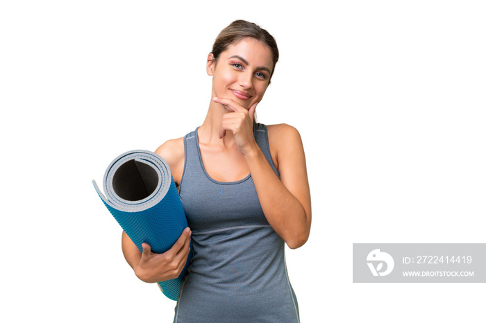 Pretty Young Uruguayan sport woman going to yoga classes while holding a mat over isolated background happy and smiling