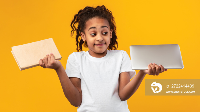 Black girl standing with book and tablet in studio