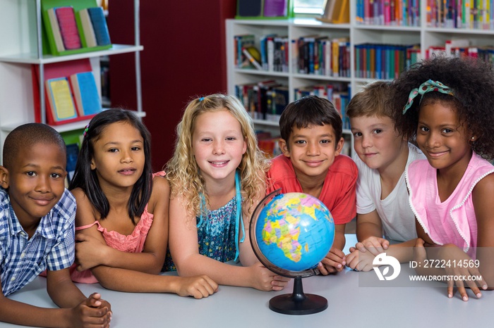 Smiling children with globe on table