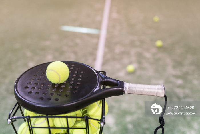 Paddle tennis rackets, balls and basket in court