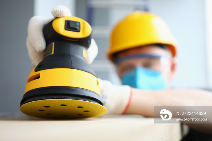 Construction foreman in helmet mask works with grinder