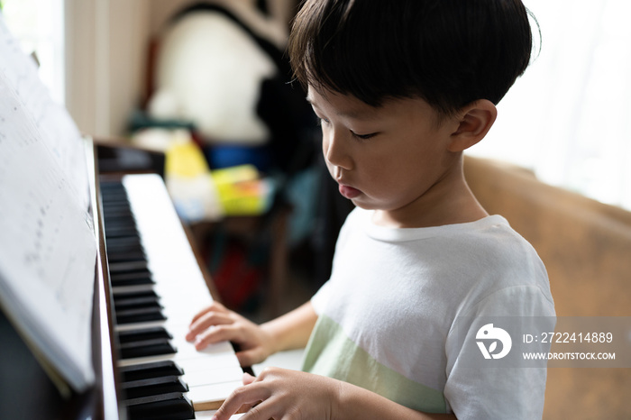 A boy is studying piano online with tablet.