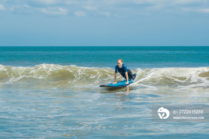 Joyful young woman beginner surfer with blue surf has fun on small sea waves. Active family lifestyle, people outdoor water sport lesson and swimming activity on surf camp summer vacation