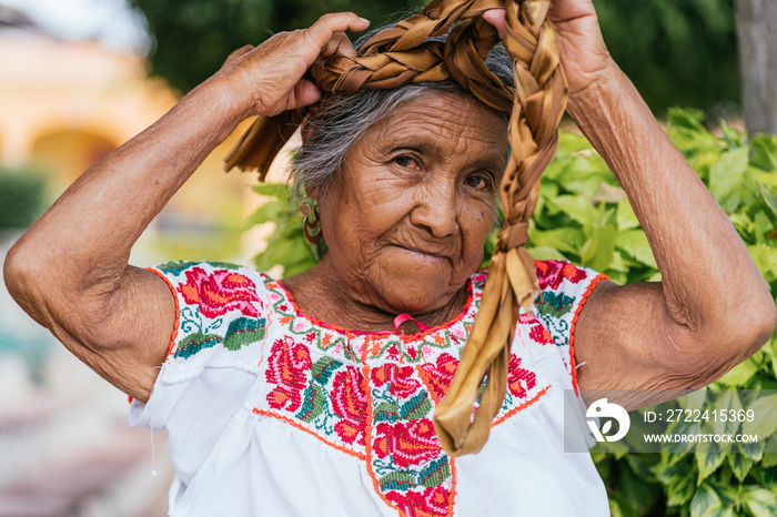 old mexican woman combing hair. adult woman looking at camera, wears typical Mexican costume