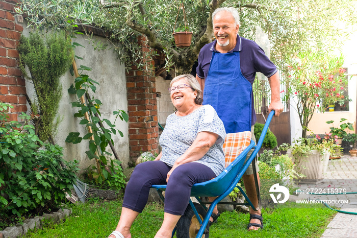 old man carry the aged wife at home outside in the jardin. laughing and happy together senior couple playing and joking at home. nice leisure activity outdoor for happiness lifestyle.