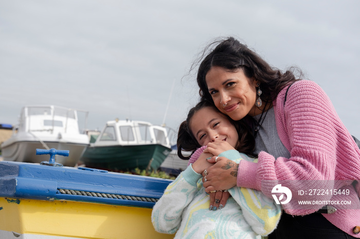 Portrait of smiling mother embracing daughter in harbor