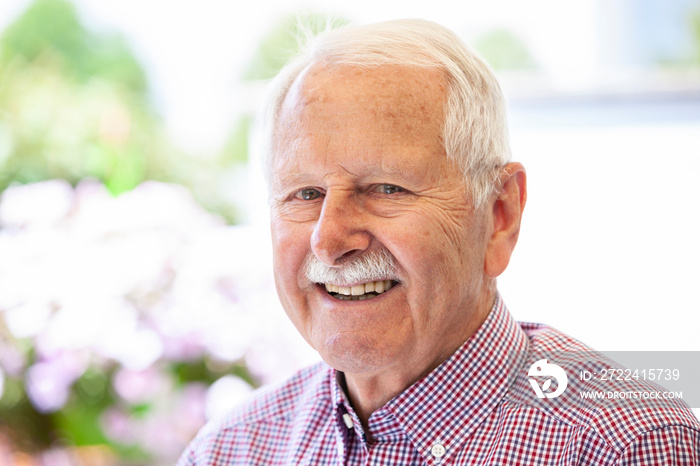 portrait of senior, old men smile and is relaxed in his garden with a white wand