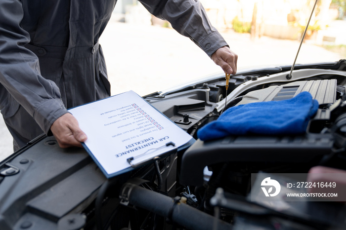 Maintenance engineer or auto mechanic pulls engine oil dipstick to inspect and check mileage of car, oil change ready to check information Enter record details in the car maintenance service file.