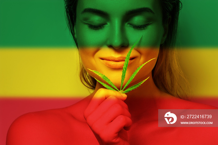 Beautiful woman with a cannabis leaf in colors of Rastafarian flag