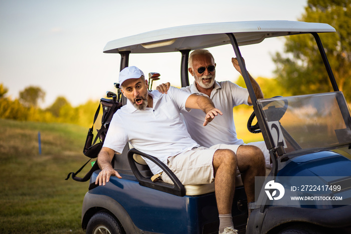 Two older friends are riding in a golf cart.